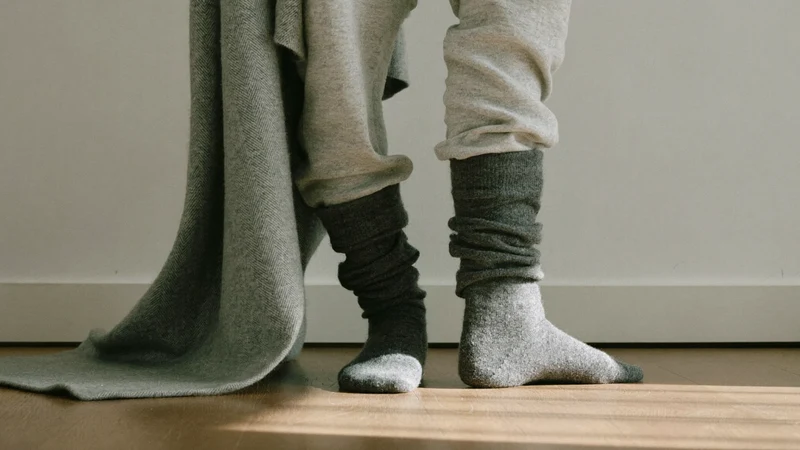 Světlý skandinávský kout s nohama v vlněných ponožkách u měkké deky