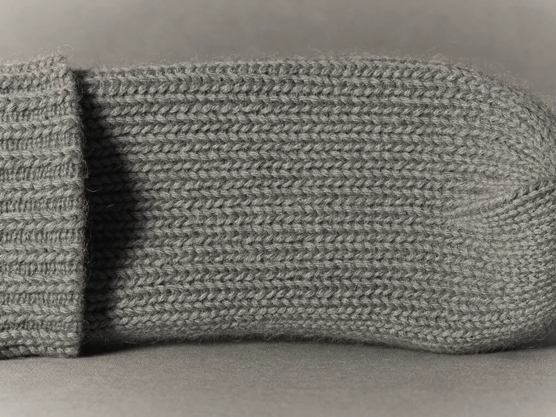 Detailní záběr na pletený vlněný materiál s viditelnou strukturou ok